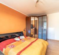 Schlafzimmer mit einem großen Bett, einem Einbauschrank und einem Bodenbelag in Holzoptik in einer 3-Zimmer-Wohnung.