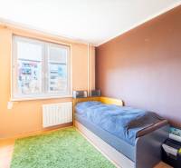 Kinderzimmer mit Bett und grünem Teppich in einer 3-Zimmer-Wohnung.