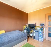 Ein Zimmer in einer 3-Zimmer-Wohnung mit einem Bett, einem Schreibtisch und einem Boden in Holzoptik.