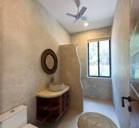 Badezimmer mit Waschbecken, rundem Teppich und Ventilator. Hausbau.