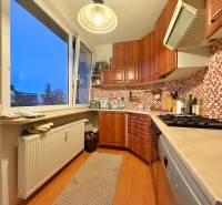 Küche in einer 3-Zimmer-Wohnung mit hellen Möbeln und einem Boden in Holzoptik.