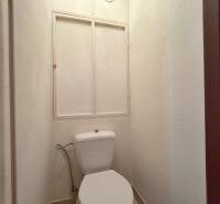 Toilette in einer 3-Zimmer-Wohnung mit einfachem Design und weißen Wänden.