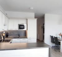 Die Küche einer 2-Zimmer-Wohnung mit weißen Schränken und einem Esstisch, der Boden hat eine Holzoptik.