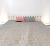 Schlafzimmer mit Bett, zwei Kissen und Nachttischen in einer Zweizimmerwohnung.