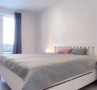 Schlafzimmer in einer 2-Zimmer-Wohnung mit hellen Möbeln und einem Boden in Holzoptik.