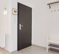 Der Eingangsflur mit hellen Wänden und einem Boden in Holzoptik führt ins Schlafzimmer.