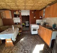 Eine Küche mit älteren Möbeln, ein Boden mit Holzdekor, sichtbarer Essbereich.