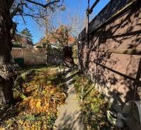 Ein schmaler Garten in Bratislava - Ružinov auf der Stredná Straße mit einem Gehweg und Bäumen.