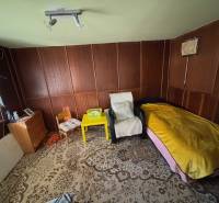 Ein Zimmer mit Stühlen, einem Bett, einem Schrank und einem dekorativen Teppich in den Gärten.