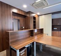 Ein Büro mit einem Boden in Holzoptik und einer Kochnische, breiter Holztheke.