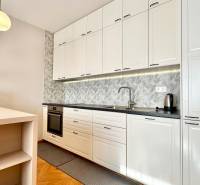 Küche in einer 3-Zimmer-Wohnung mit weißen Schränken und einem Boden in Holzoptik.