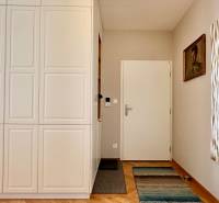 Eingangsbereich mit weißem Schrank, Spiegel, Bild und Boden mit Holzdekor in einer 3-Zimmer-Wohnung.