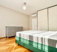 Helles Schlafzimmer mit Bett, Schrank und Boden in Holzoptik in einer 3-Zimmer-Wohnung.