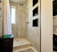 Badezimmer einer 3-Zimmer-Wohnung mit Waschmaschine, Wanddusche und Heizkörper mit Handtüchern.