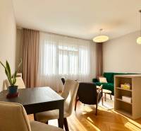 Wohnzimmer mit Holzdekorboden, grünem Sofa und Esstisch in einer 3-Zimmer-Wohnung.