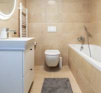 Ein beige gehaltenes Badezimmer mit Badewanne, Waschbecken und Spiegel in einer Einzimmerwohnung.