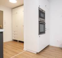 Küche in einer Einzimmerwohnung mit weißen Schränken und einem Boden in Holzoptik.