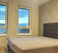 Schlafzimmer mit großem Fenster und Bett in einer 2-Zimmer-Wohnung, Boden mit Holzdekor.