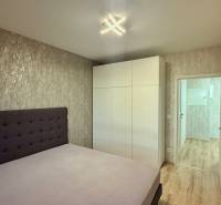 Schlafzimmer mit Bett, weißem Schrank und Boden mit Holzdekor in einer 2-Zimmer-Wohnung.