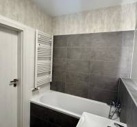 Badezimmer mit Badewanne und dunklen Fliesen in einer 2-Zimmer-Wohnung.