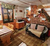 Innenraum einer Hütte mit Sofa, Holzboden, Esstisch und Treppe.