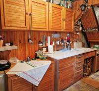 Eine Küche in einer Hütte mit Holzschränken und einer weißen Arbeitsplatte, gemütliche Atmosphäre.