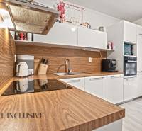 Küche in einer 3-Zimmer-Wohnung mit weißen Schränken und einem Boden in Holzoptik.