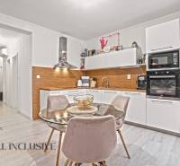 Küche in einer 3-Zimmer-Wohnung mit weißen Schränken, Boden in Holzoptik und Esstisch.