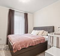 Schlafzimmer in einer 3-Zimmer-Wohnung mit einem Bett und einem Kinderbett, Boden mit Holzdekor.