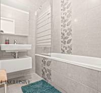 Badezimmer in einer 3-Zimmer-Wohnung mit Duschwanne, Waschbecken und dekorativen Fliesen an den Wänden.