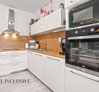 Moderne Küche in einer 3-Zimmer-Wohnung mit weißen Schränken und Holzboden.