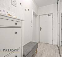 Der Flur in der 3-Zimmer-Wohnung mit weißen Möbeln und einem Boden in Holzoptik.