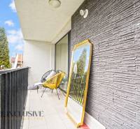 Der Balkon einer 3-Zimmer-Wohnung mit einem dekorativen Spiegel und einem bequemen Sessel.