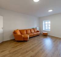 Wohnzimmer mit orangem Sofa und Holzboden in einer 2-Zimmer-Wohnung.