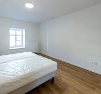 Schlafzimmer mit Bett und Boden in Holzoptik in einer 2-Zimmer-Wohnung.