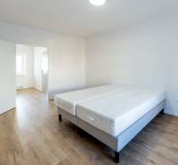 Helles Zimmer mit Doppelbett und Holzboden in einer 2-Zimmer-Wohnung.