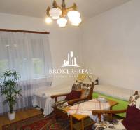 Gemütliches Zimmer in einem Einfamilienhaus mit Sesseln, Betten und einem Boden in Holzoptik.