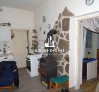 Eine Küche in einem Einfamilienhaus mit einem Herd, einem Ofen und einer Steinverkleidung an der Wand.