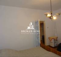 Schlafzimmer in einem Einfamilienhaus mit einfacher Einrichtung und Retro-Heizung.