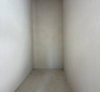 Ein enger, leerer Innenraum eines Einfamilienhauses mit Betonboden und weißen Wänden.