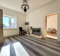 Ein Zimmer in einem Einfamilienhaus mit weißen Wänden, einem Boden in Holzoptik und einem großen Fenster.