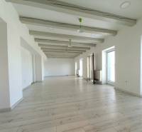 Helle Büros mit Holzboden und großen Fenstern.