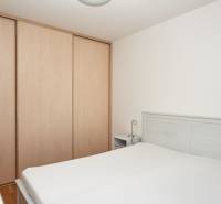 Schlafzimmer in einer 2-Zimmer-Wohnung mit Bett, Schrank und weißen Wänden.