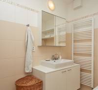 Badezimmer in einer 2-Zimmer-Wohnung mit weißen Möbeln, Spiegel und Handtuch.