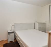 Schlafzimmer in einer 2-Zimmer-Wohnung mit Doppelbett, Nachttisch und Kommode.