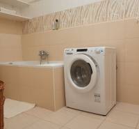 Badezimmer mit Badewanne, Waschmaschine und Regal in einer 2-Zimmer-Wohnung.