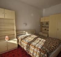 Ein Schlafzimmer in einem Einfamilienhaus mit hellen Möbeln und gemustertem Bettüberwurf.