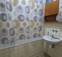 Badezimmer in einem Einfamilienhaus, Badewanne mit Vorhang, Waschbecken mit Seife und Spiegel.