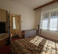 Ein Schlafzimmer in einem Einfamilienhaus mit einem Fernseher und Bettwäsche mit Blumenmuster.