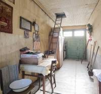 Innenraum eines Einfamilienhauses mit einer Leiter neben einer bestickten Tapisserie. Boden mit Holzdekor.